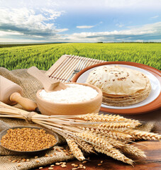 Wheat flour, Chapati, Roti, Bunch of wheat ears, dried grains, flour in terracota bowl on Wheat Farm background. Cereals harvesting, bakery products.