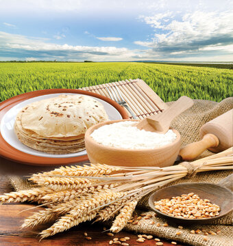 Wheat flour, Chapati, Roti, Bunch of wheat ears, dried grains, flour in terracota bowl on Wheat Farm background. Cereals harvesting, bakery products.