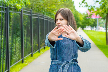A young girl stretches her hand forward with an open palm as a STOP sign. The concept is irritation...