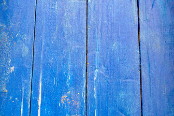 Fototapeta na wymiar Background with a wooden surface painted with bright yellow paint. Cracked old paint on a wooden surface
