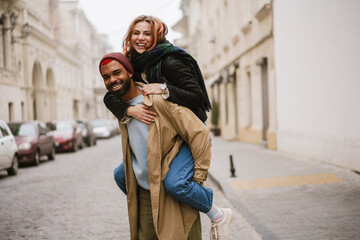 Happy afro american man giving piggyback ride his laughing girlfriend