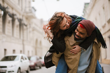 Happy afro american man giving piggyback ride his laughing girlfriend