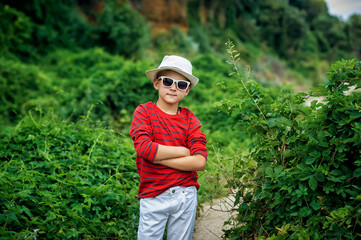 Naklejka na ściany i meble Beautiful boy in sunglasses and hat on a walk