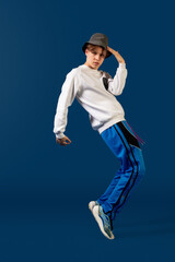 Fototapeta na wymiar Balancing. Old-school fashioned young man dancing isolated on blue studio background. Artist fashion, motion and action concept, youth culture, fashion returning. Young caucasian curly boy.