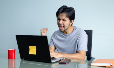 young man was excited while using the laptop, young man with expression of triumph,
