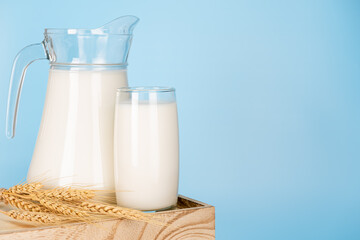 Jug and bottle of fresh milk glass on barley wheat and wooden crate box. Raw milk is high in calcium and protein to drink for all ages. Milk consumption nutritious and healthy dairy products concept.