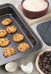 Chocolate chip cookies on a baking tray with ingredients