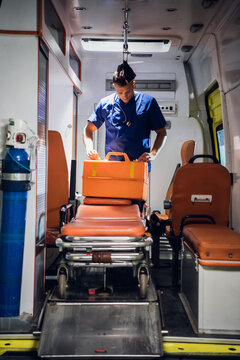 A young doctor in a medical uniform packs his medical bag in the ambulance car.