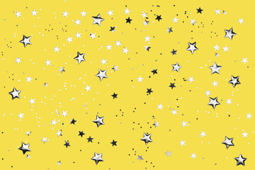 Yellow background with shiny silver glitter on it. Dots, stars and little sparkles in flat lay...