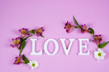 The word love on a pink background with alstroemeria flowers