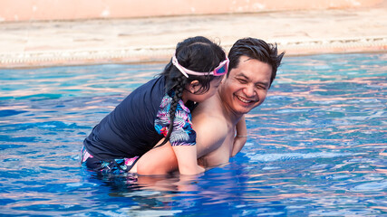 Happy father with little daughter in swimming pool at water park with smile