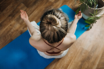 Young woman sitting on yoga pose enjoy meditation do yoga exercise at home. Mental health, self...