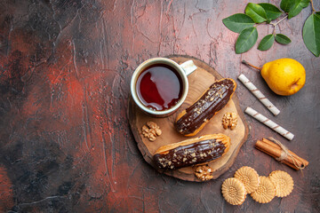 top view cup of tea with delicious choco eclairs on dark background sweet biscuit cake