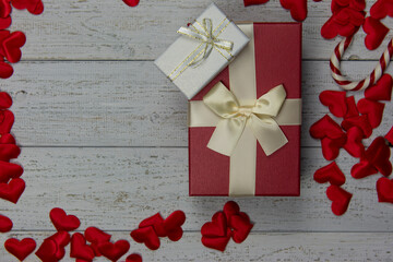gift boxes for the holiday Valentine's Day. Red and white boxes with gold ribbons. White wooden background and many red hearts. Valentine's day concept