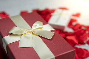gift boxes for the holiday Valentine's Day. Red and white boxes with gold ribbons. White wooden background and many red hearts. Valentine's day concept