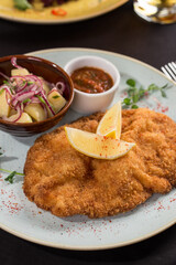 Homemade Breaded German Weiner Schnitzel with Potatoes and sauce on the table at restaurant