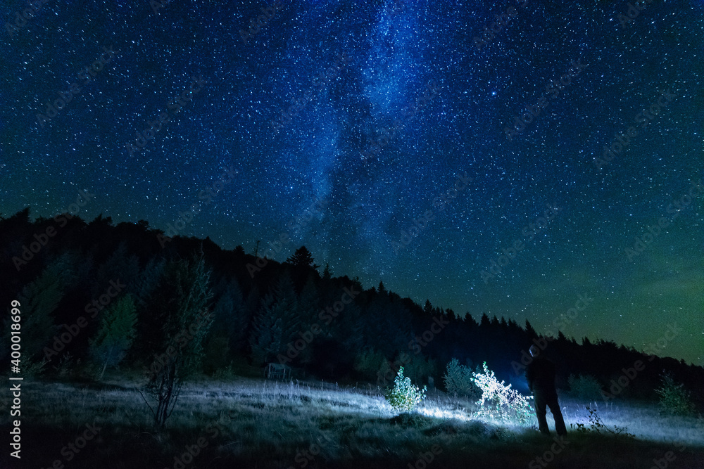 Wall mural fantastic starry night with galaxy milky way with a tourist and a tent on the mountain range in the 