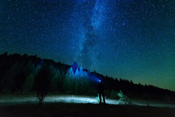 Fantastic starry night with galaxy Milky Way with a tourist and a tent on the mountain range in the Ukrainian Carpathians	