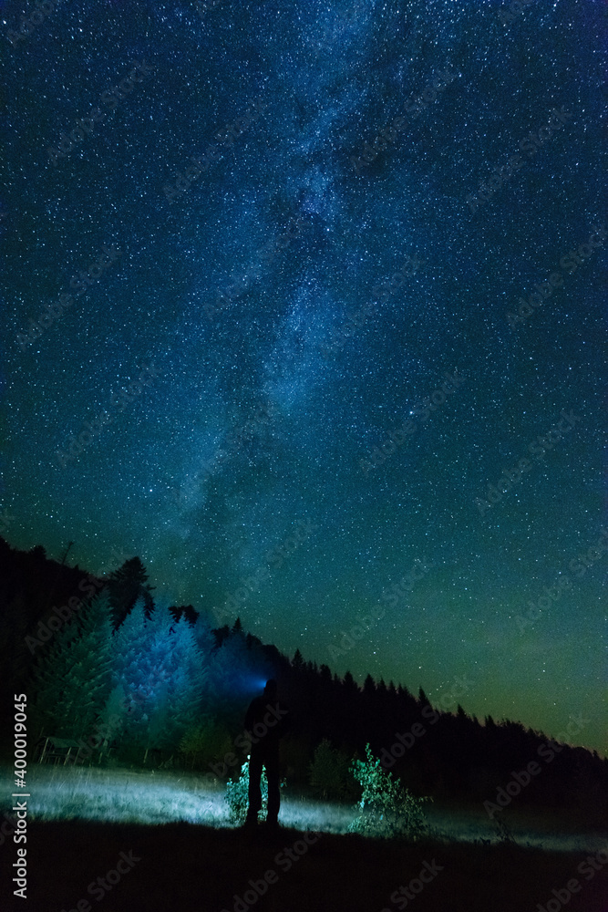 Wall mural fantastic starry night with galaxy milky way with a tourist and a tent on the mountain range in the 