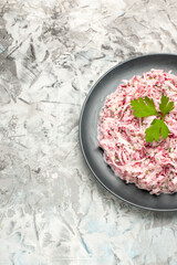 Vertical view of tasty chicken salad with mayonnaise and beet served with green on ice background