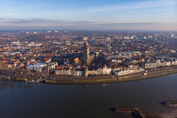 Fototapeta na wymiar Aerial cityscape panorama of the Dutch medieval city of Deventer in The Netherlands seen from the other side of the river IJssel that passes it at sunrise