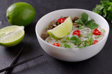 Pho Bo - Vietnamese fresh rice noodle soup with beef, herbs, lime and chili. Vietnamese national...