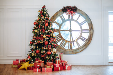 Beautiful Christmas living room with decorated Christmas tree, gifts in front of whate wall. New year tree with red and gold decor balls