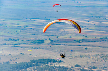 Paragliding in the mountains. Paragliders group fly over valley