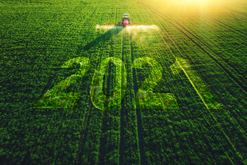 2021 Happy New Year concept and Aerial view of farming tractor plowing and spraying on field.