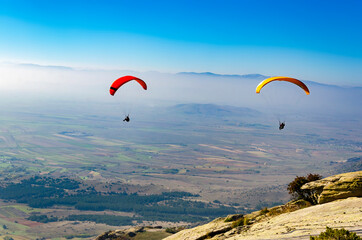 Paragliding flight with blue sky and misty valley