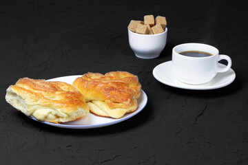 Pastry and cup of coffee on a black background. Homemade cake. Cane sugar. Fresh baked cake. Breakfast