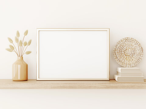 Poster art mockup with horizontal gold metal frame, dried grass in vase, basket plate and books on empty warm beige wall background. Boho interior decoration. A4, A3 format. 3d rendering, illustration