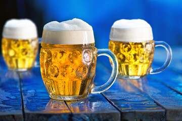 Glasses of beer on the blue wooden background.