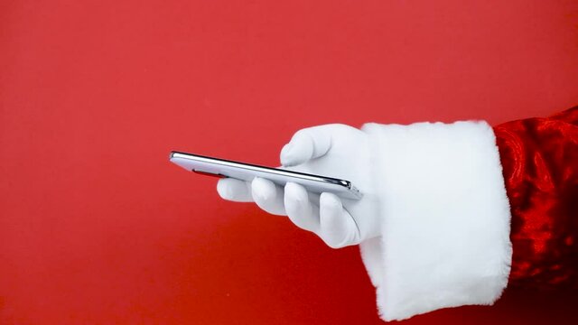 Santa Claus hand holding a smartphone with a blank screen. Mobile phone during holiday time, mockup 
