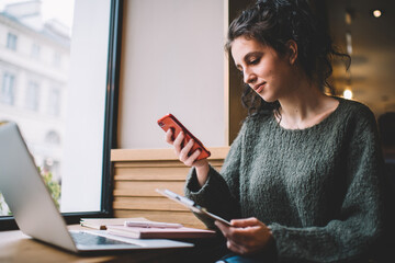 Smiling ethnic woman messaging on smartphone in cafe