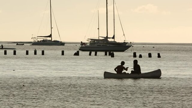 Couple of people in love canoeing in tahitian sea on the yacht scenery.