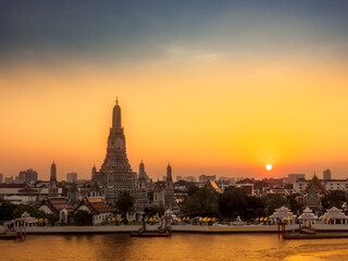 Obraz premium View of Wat Arun and Chao Phraya river at sunset. Buddhist Temple and Landmarks in Bangkok Thailand