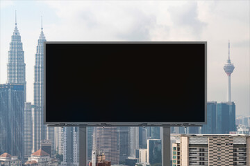 Blank black road billboard with Kuala Lumpur cityscape background at day time. Street advertising poster, mock up, 3D rendering. Front view. Concept of marketing to promote or sell services or ideas.