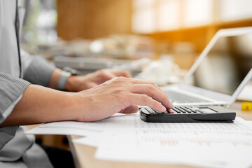 Businessman pressing on calculator for calculating cost estimating with laptop.