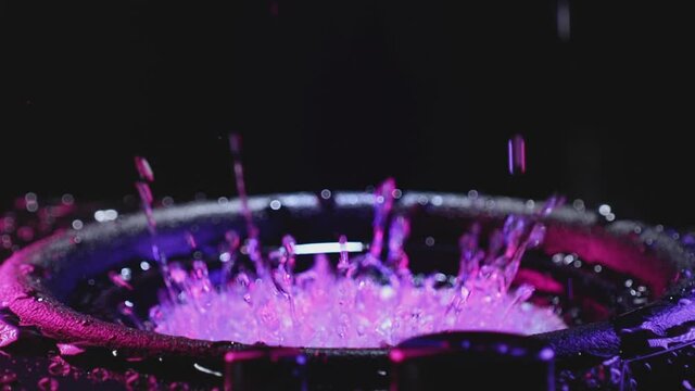 Abstract concept of powerful sound speakers throwing powder in blue neon light. Power music. A shaky speaker tosses liquid water in a neon light. Bass sound in a recording studio. Retrowave concept