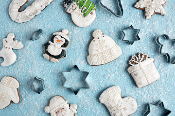 Winter Christmas pattern made with homemade cookies in shape of penguin, knitted cap, reindeer and Santa Claus on cold blue snowy winter background. Minimal food baking concept. Flat lay, top view.