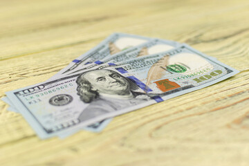 Hundred dollar bills on a wooden background.