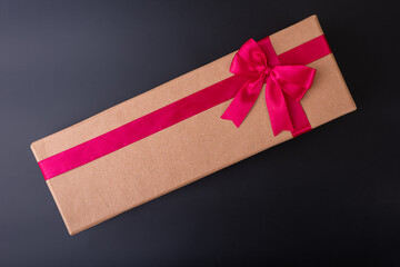 long gift box with red ribbon on black background flat lay top shot