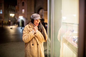 Beautiful young woman by the shop window at Christmas time