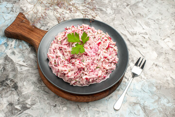 Side view of yummy salad decorated with green and knife on ice background