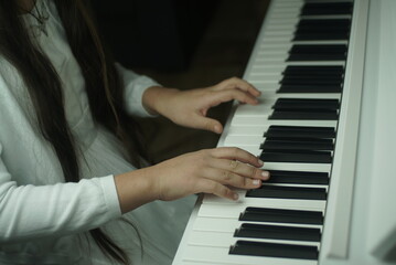 hands of a young girl on the piano keyboard