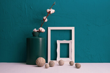 white cotton in a vase, picture frame on a blue background and decor