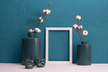 candlesticks, cotton plant in vases, photo frames on a blue background and decor