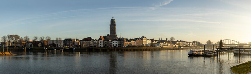 Fototapeta na wymiar Cityscape panorama of the Dutch Hanseatic medieval city of Deventer in The Netherlands seen from the other side of the river IJssel at sunrise
