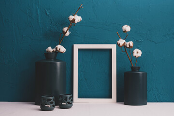 candlesticks, cotton in vases, photo frames on a blue background and decor